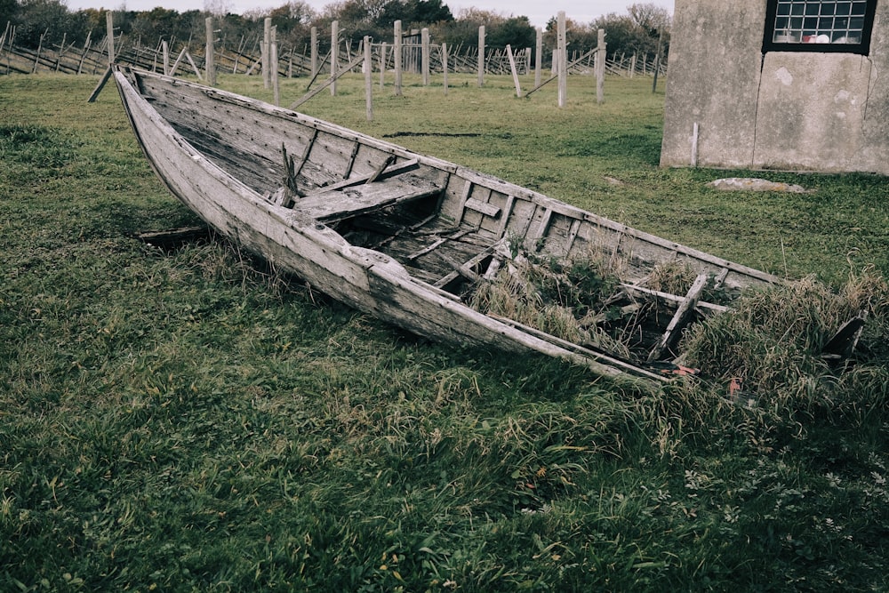 a wooden boat sitting on top of a lush green field