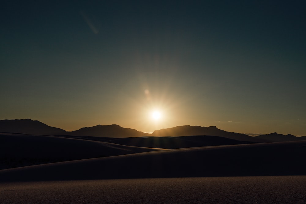 the sun is setting over the mountains in the desert