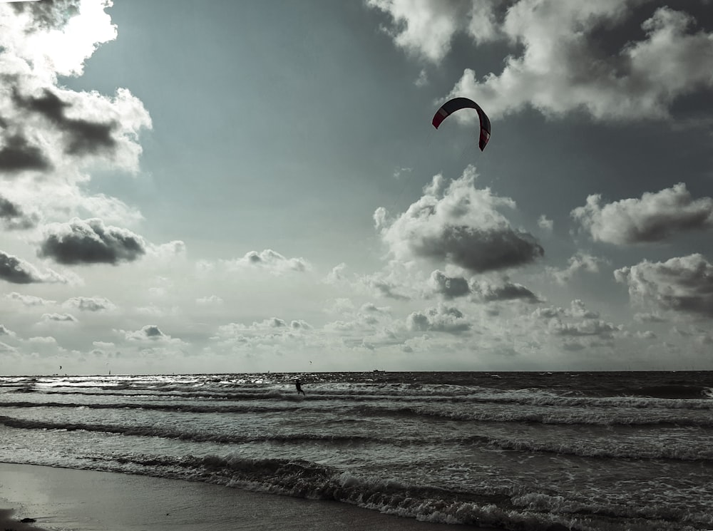 eine Person, die unter einem bewölkten Himmel auf dem Ozean parasailt