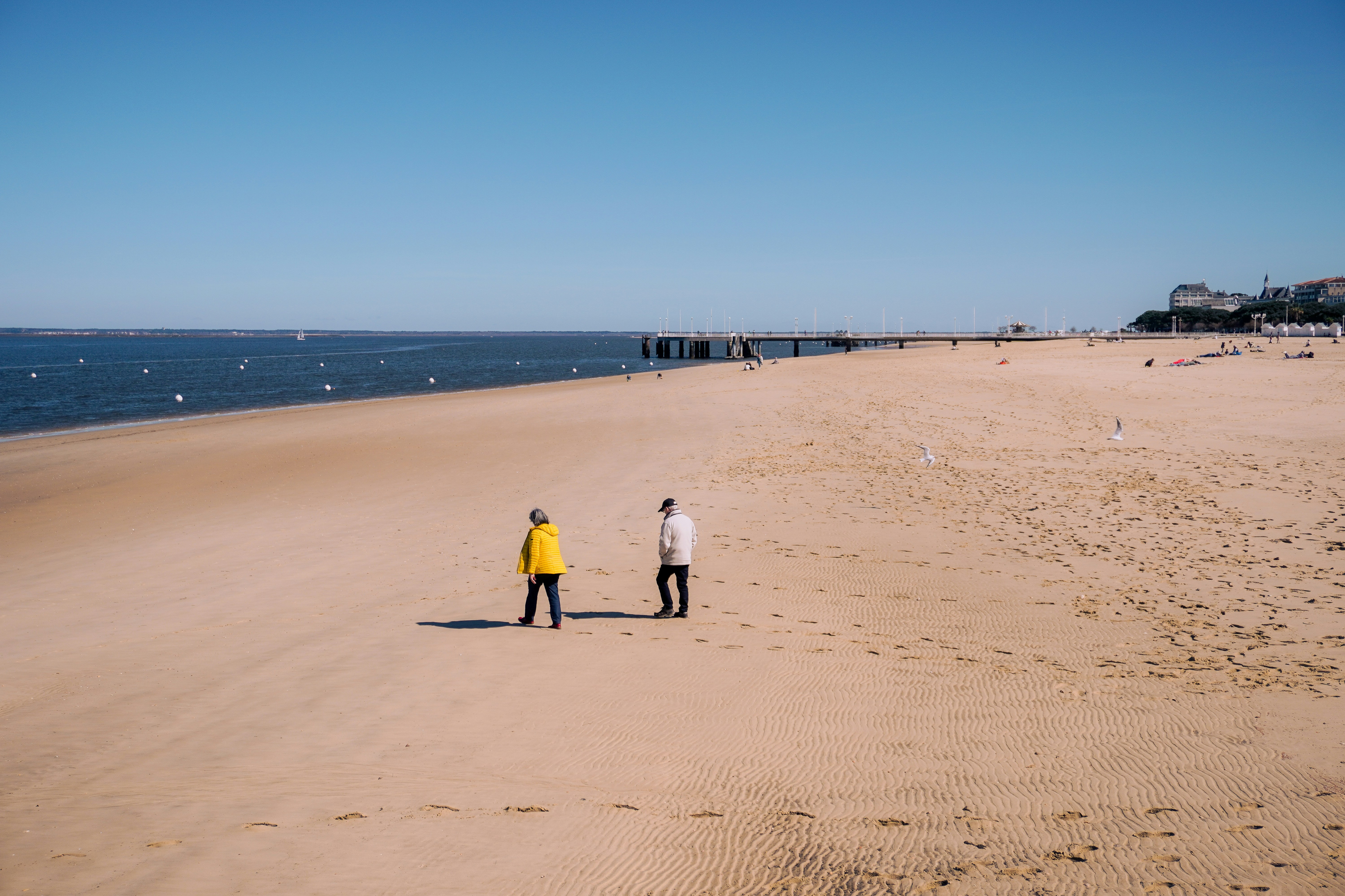 a couple of people standing on top of a sandy beach, Arcachon bay