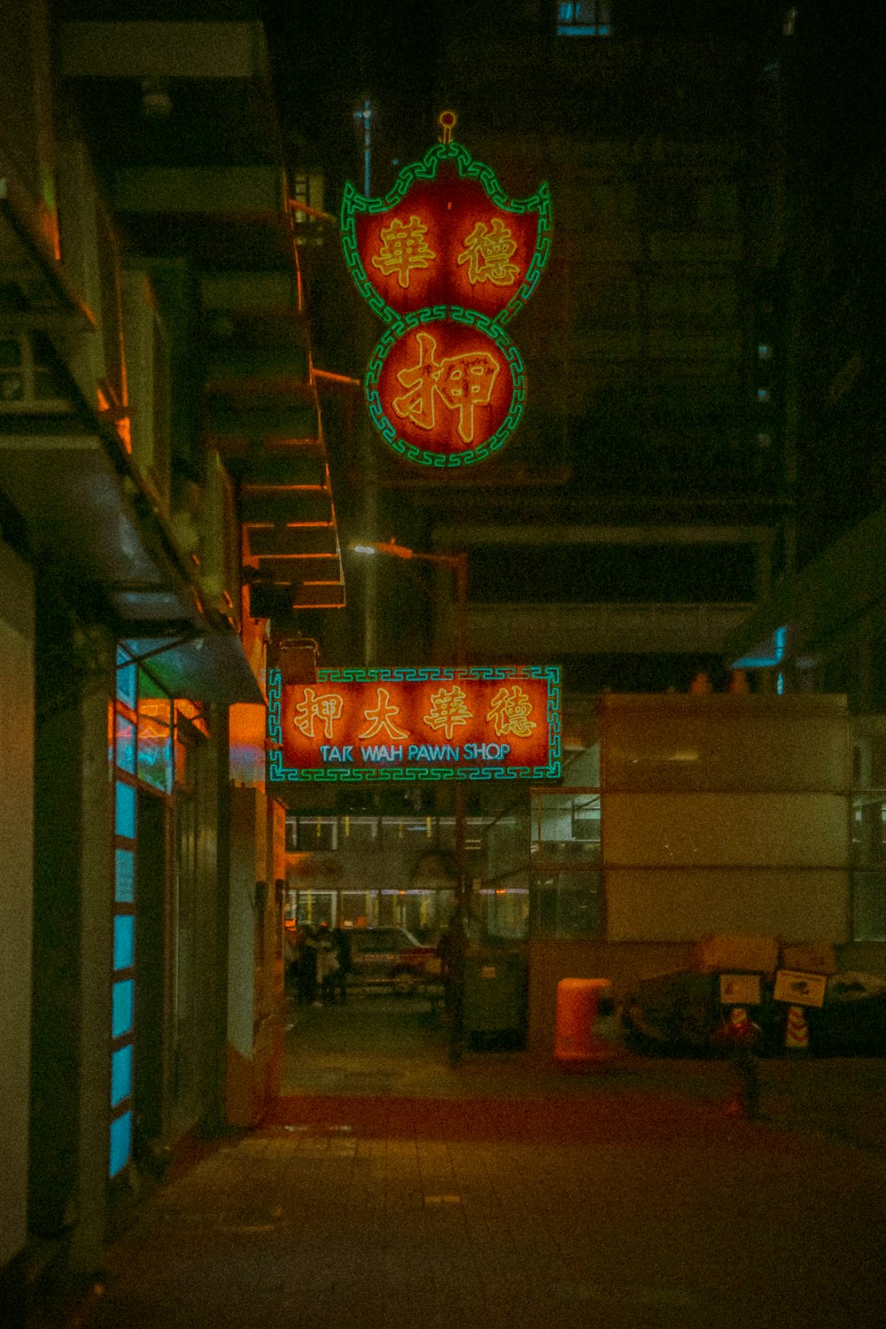 a building with neon signs hanging from it's sides