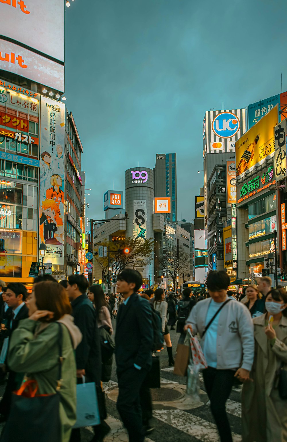 a crowd of people walking down a street next to tall buildings