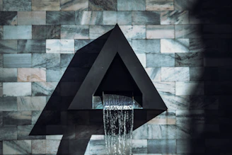 a water fountain in front of a brick wall