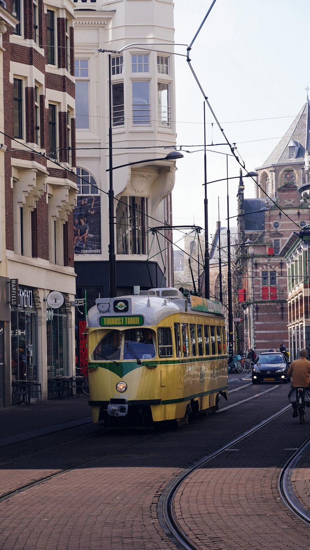 un tranvía amarillo y verde en una calle de la ciudad
