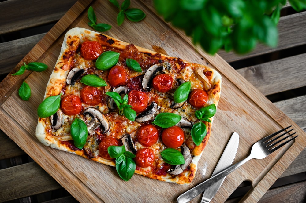 a pizza on a cutting board with a fork and knife