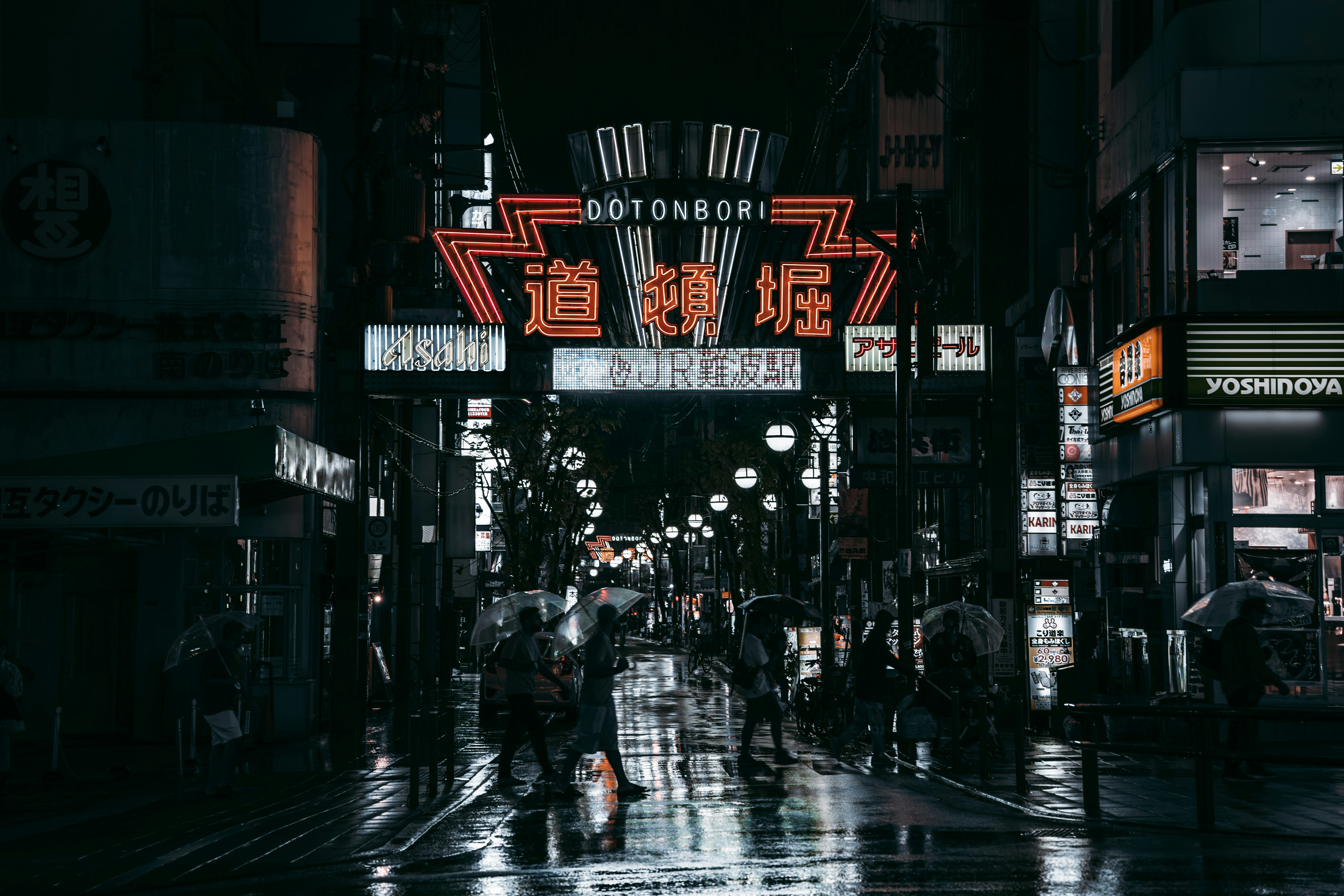 a couple of people walking down a rain soaked street