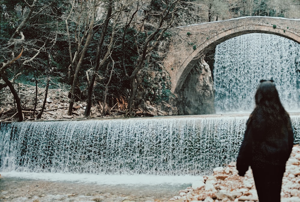 a woman standing in front of a waterfall