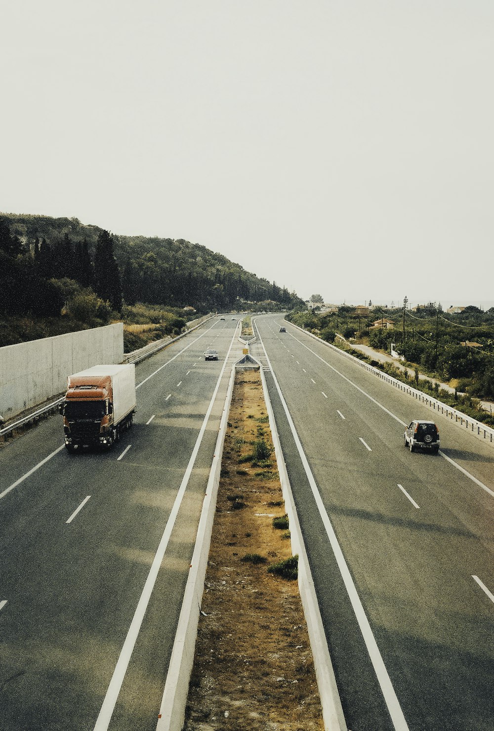 two trucks driving down a highway next to a forest