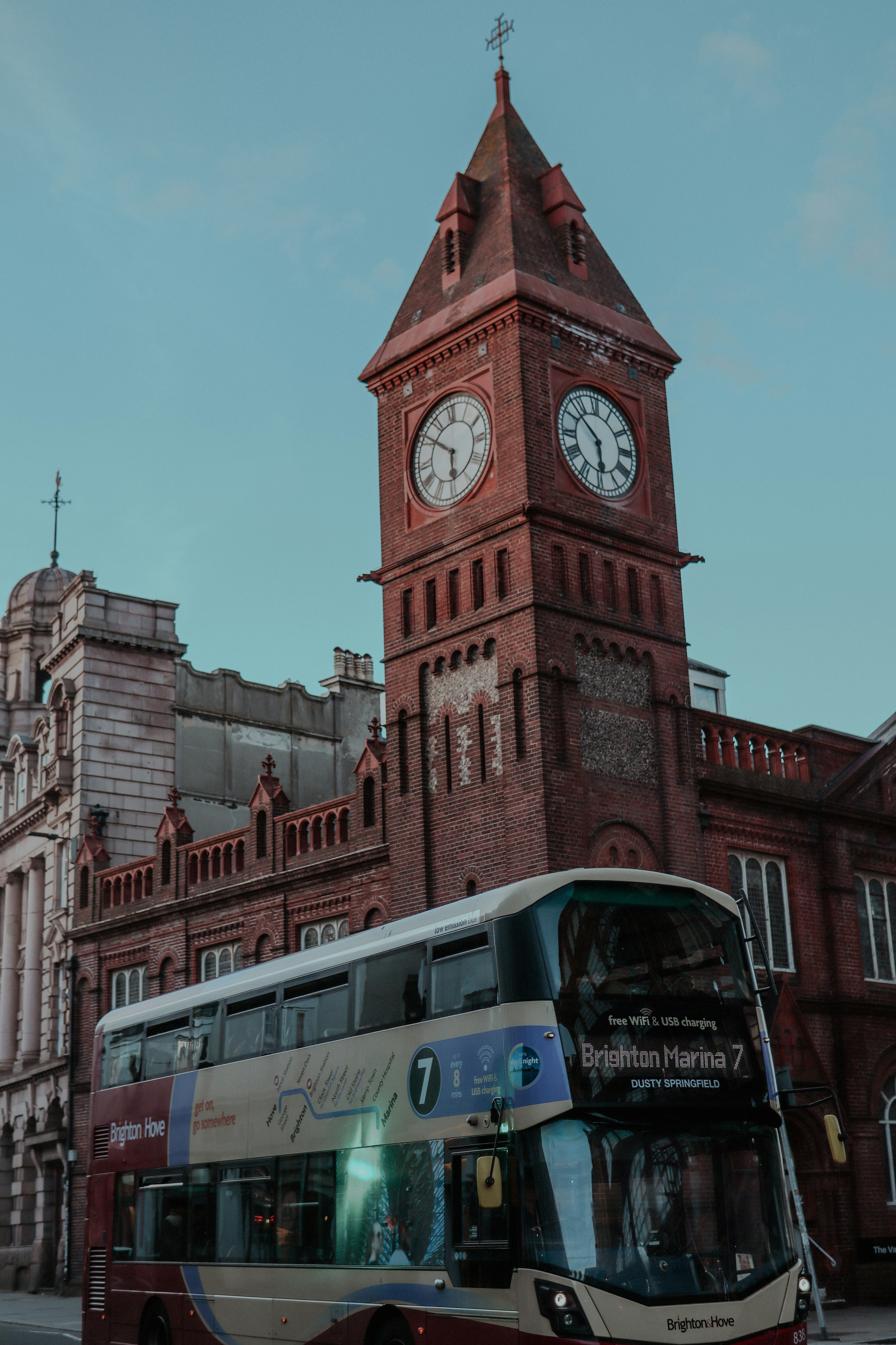 a double decker bus parked in front of a building with a clock tower