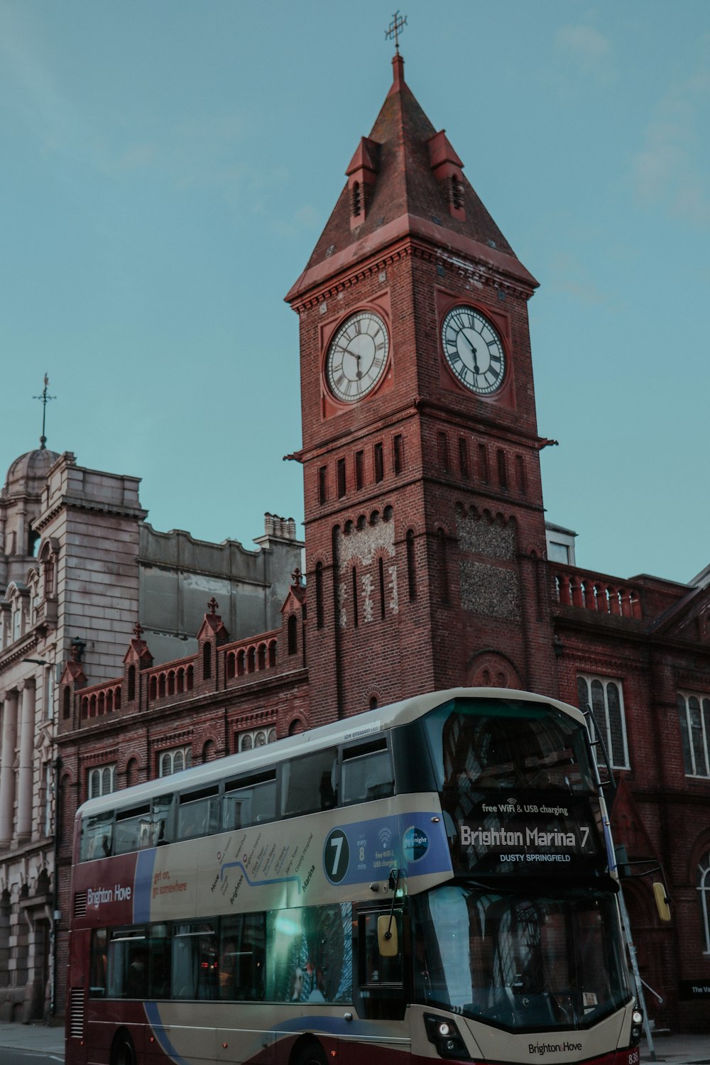 a double decker bus parked in front of a building with a clock tower