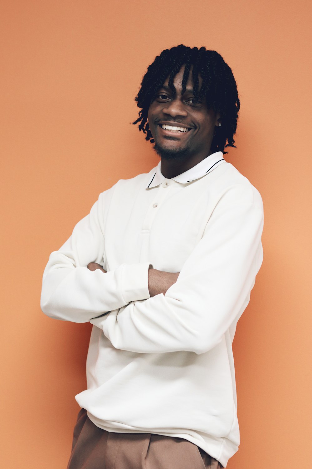 a man with dreadlocks standing in front of an orange wall