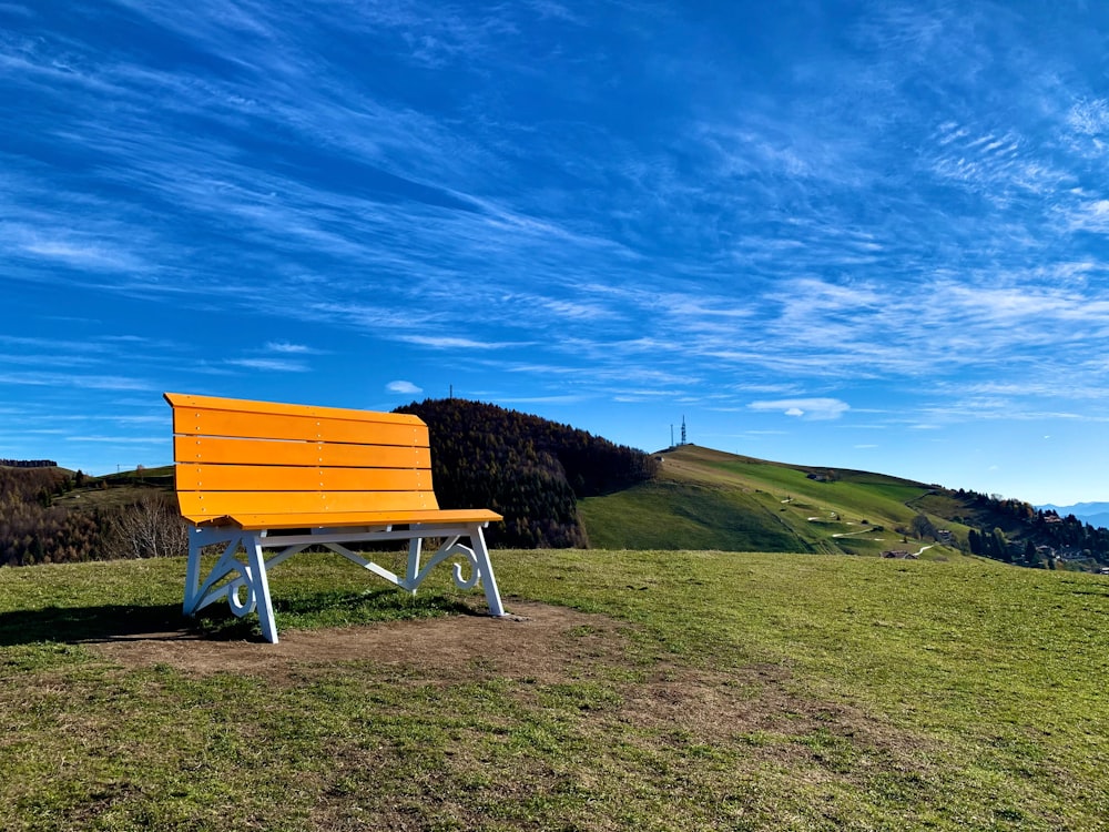 a yellow bench sitting on top of a lush green hillside