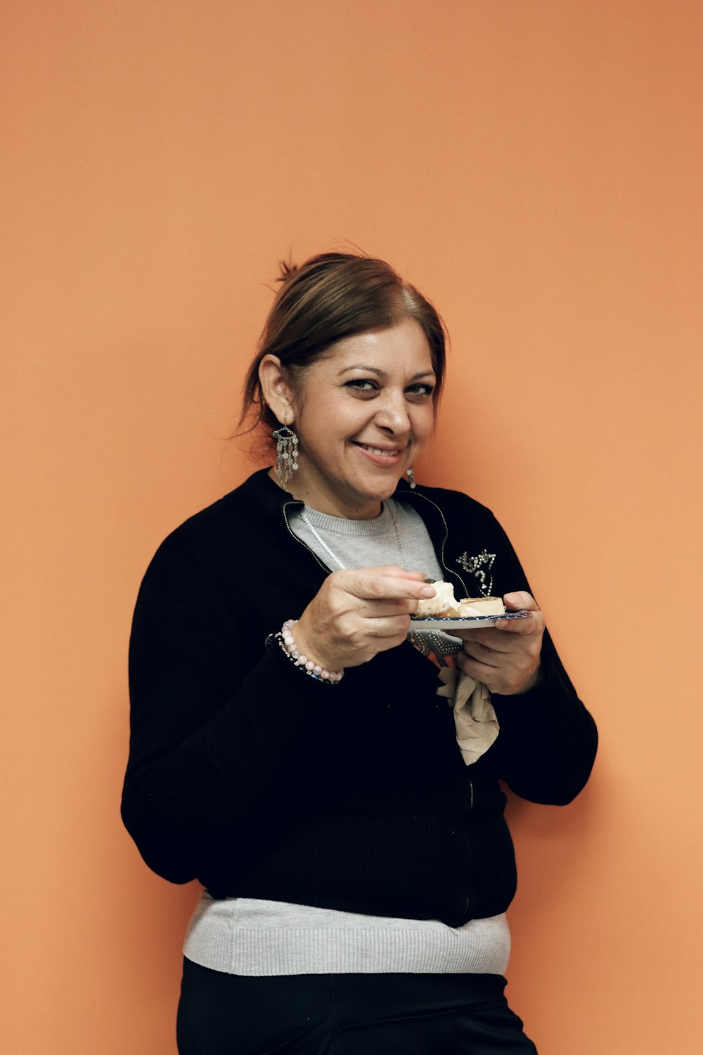 a woman holding a plate of food in front of an orange wall