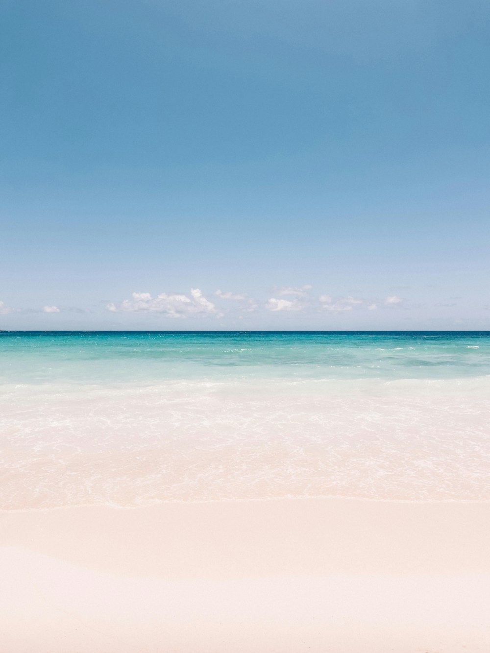 a beach scene with the ocean and a boat in the distance