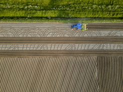 an aerial view of a tractor plowing a field