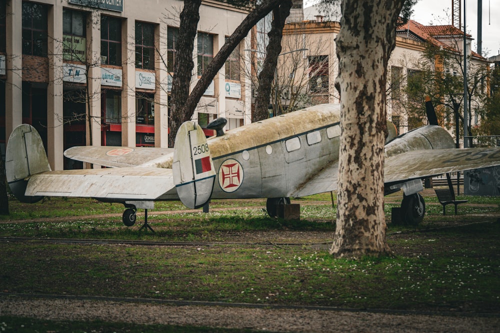 an old airplane sitting in the grass next to a tree