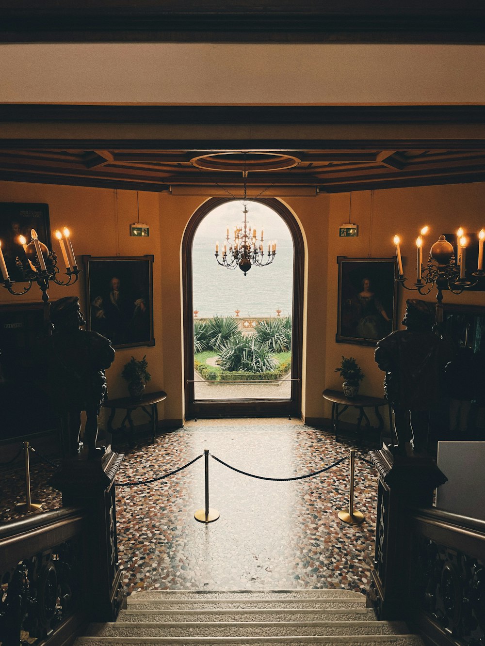 a staircase leading to an entrance with a chandelier hanging from the ceiling