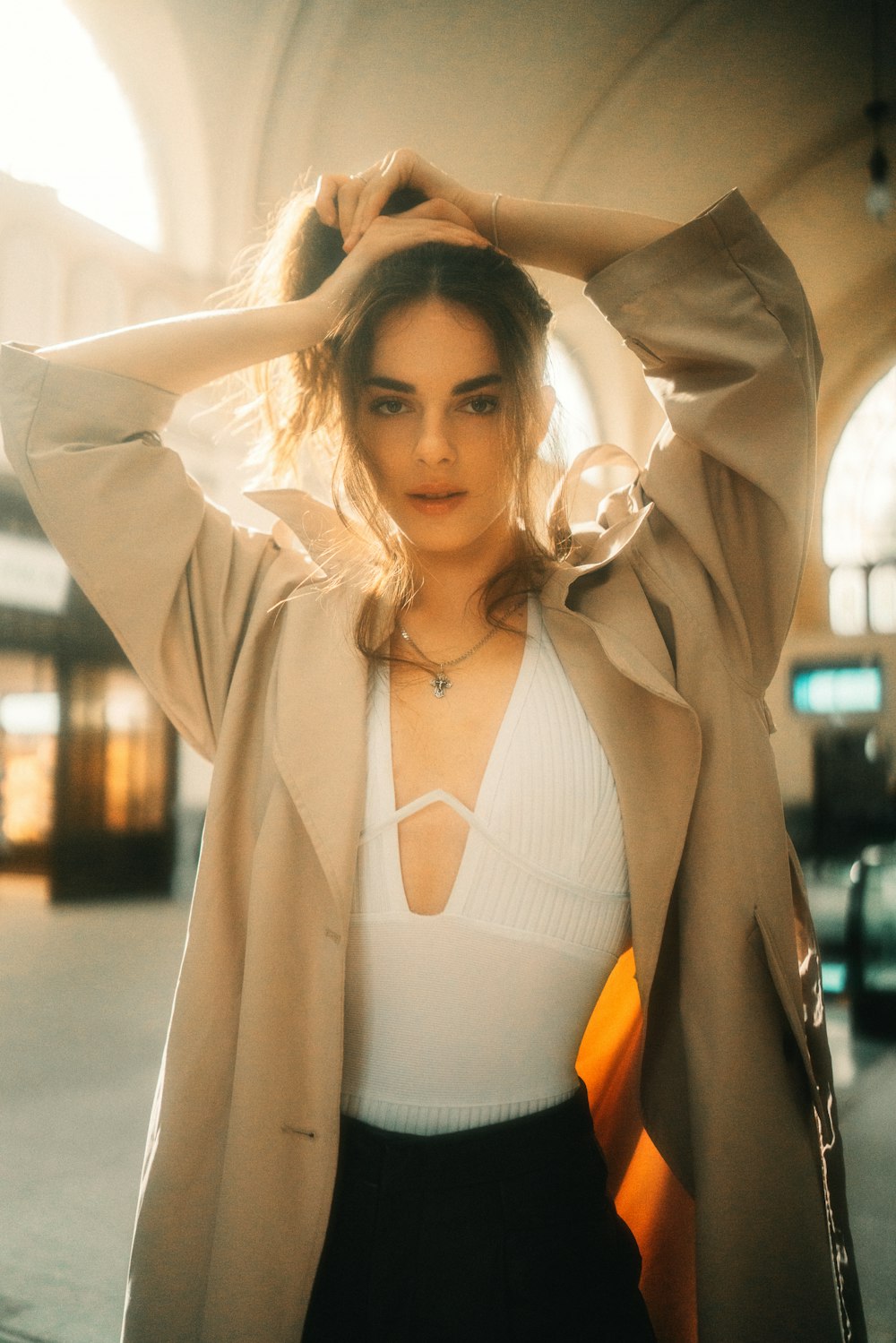 a woman in a white top and a tan coat