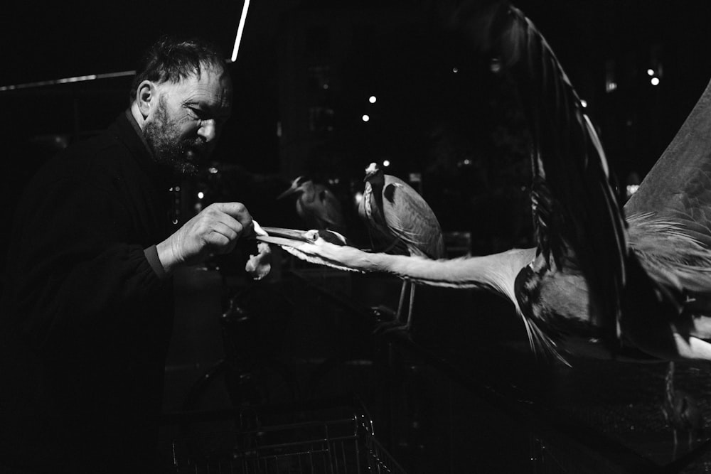 a black and white photo of a man feeding a bird