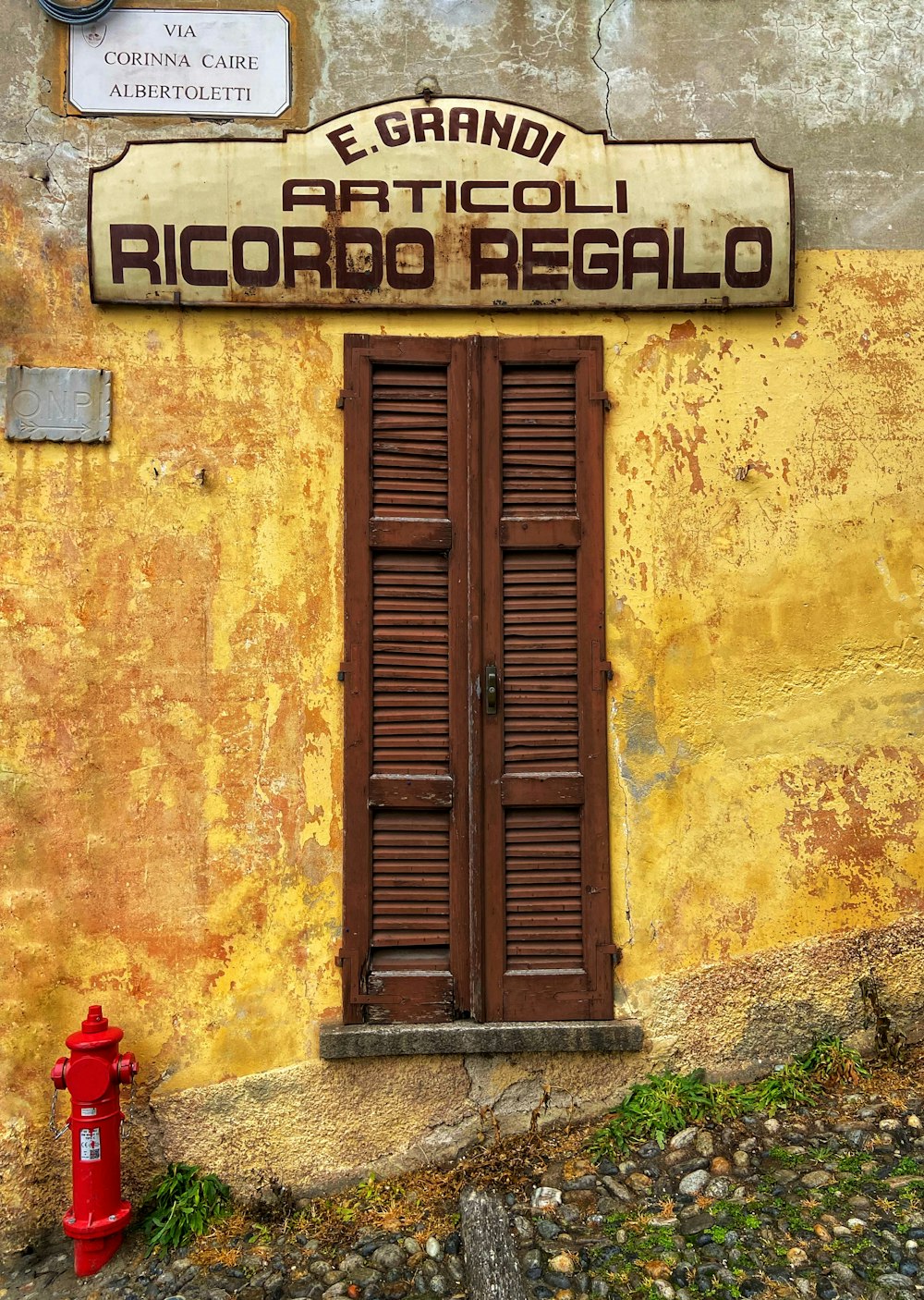 a red fire hydrant sitting in front of a yellow building