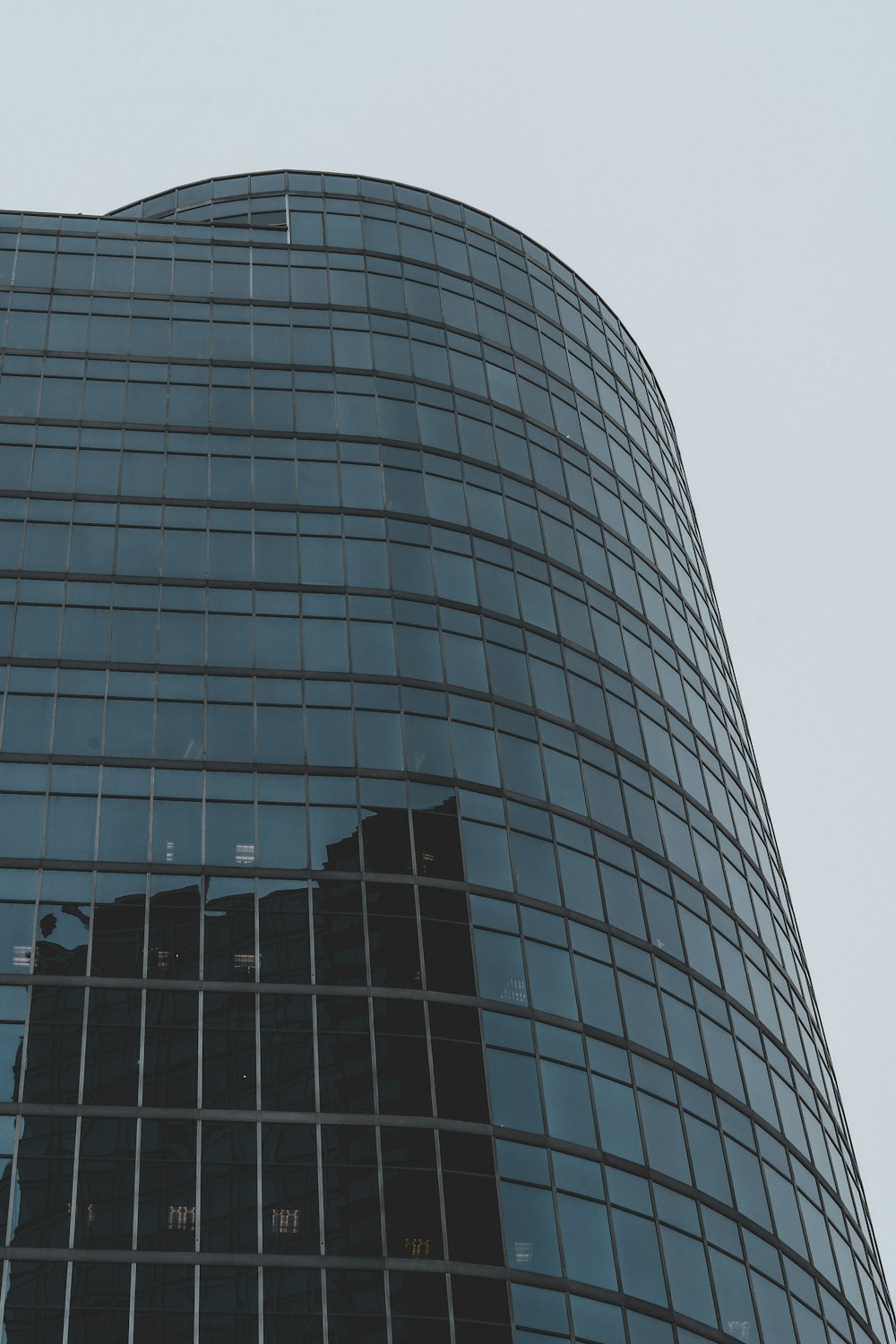 a very tall glass building with a clock on it's side