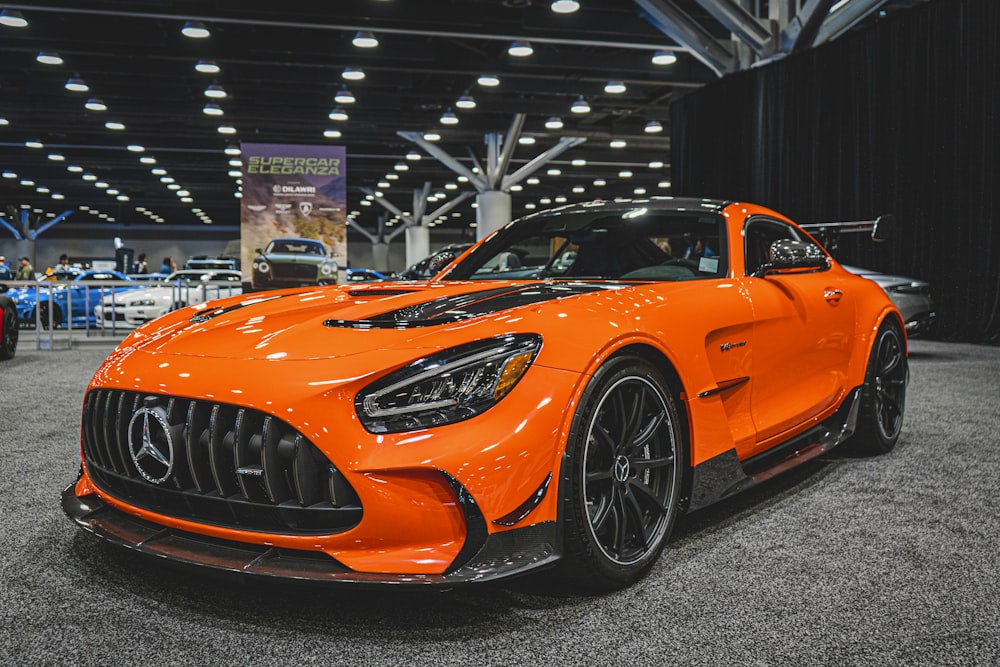 an orange mercedes sports car on display at a car show