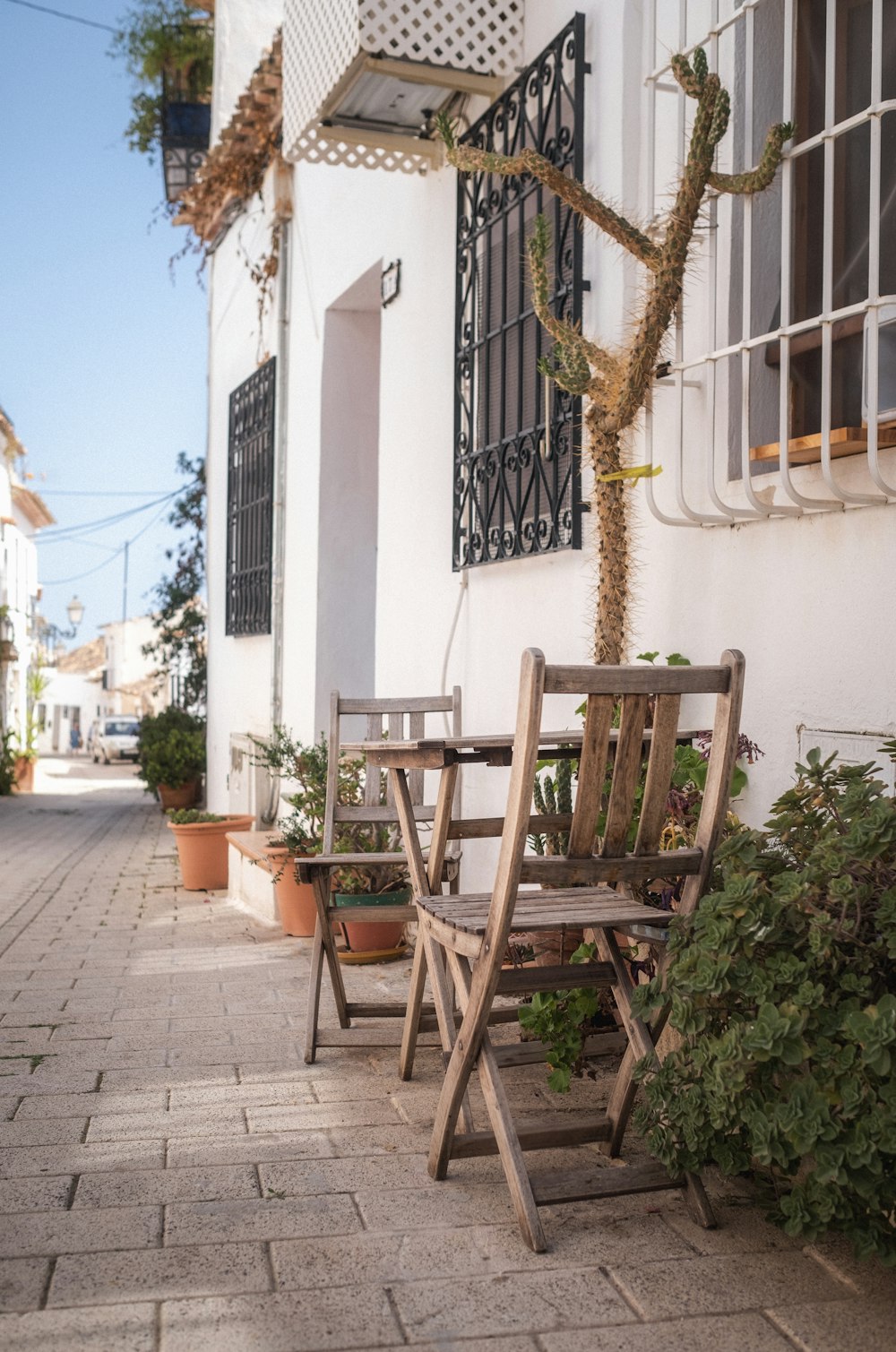 a couple of wooden chairs sitting next to a building