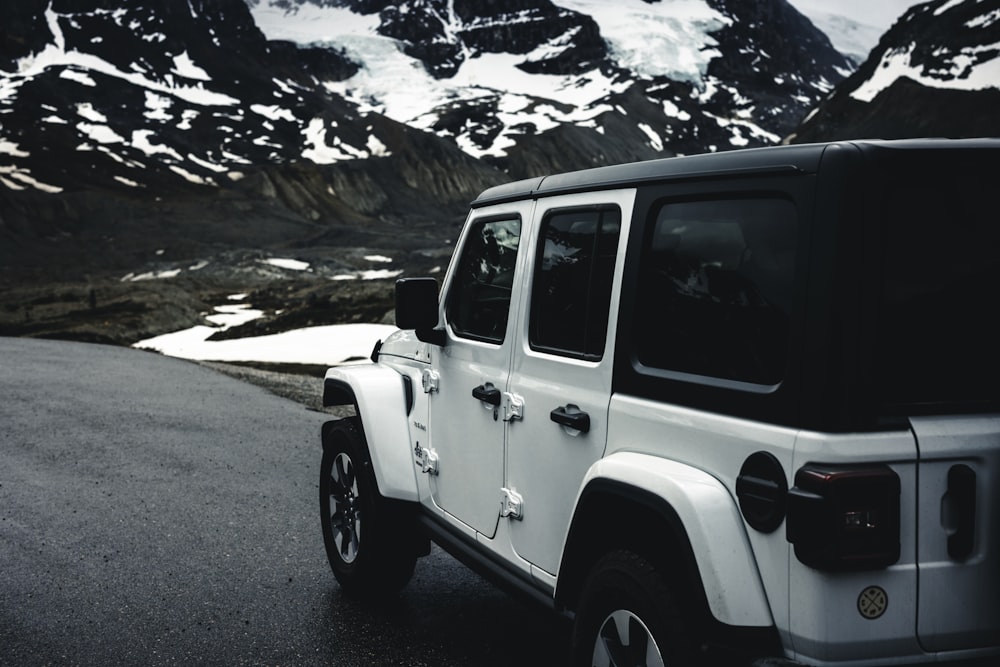 a white jeep parked on the side of a mountain road