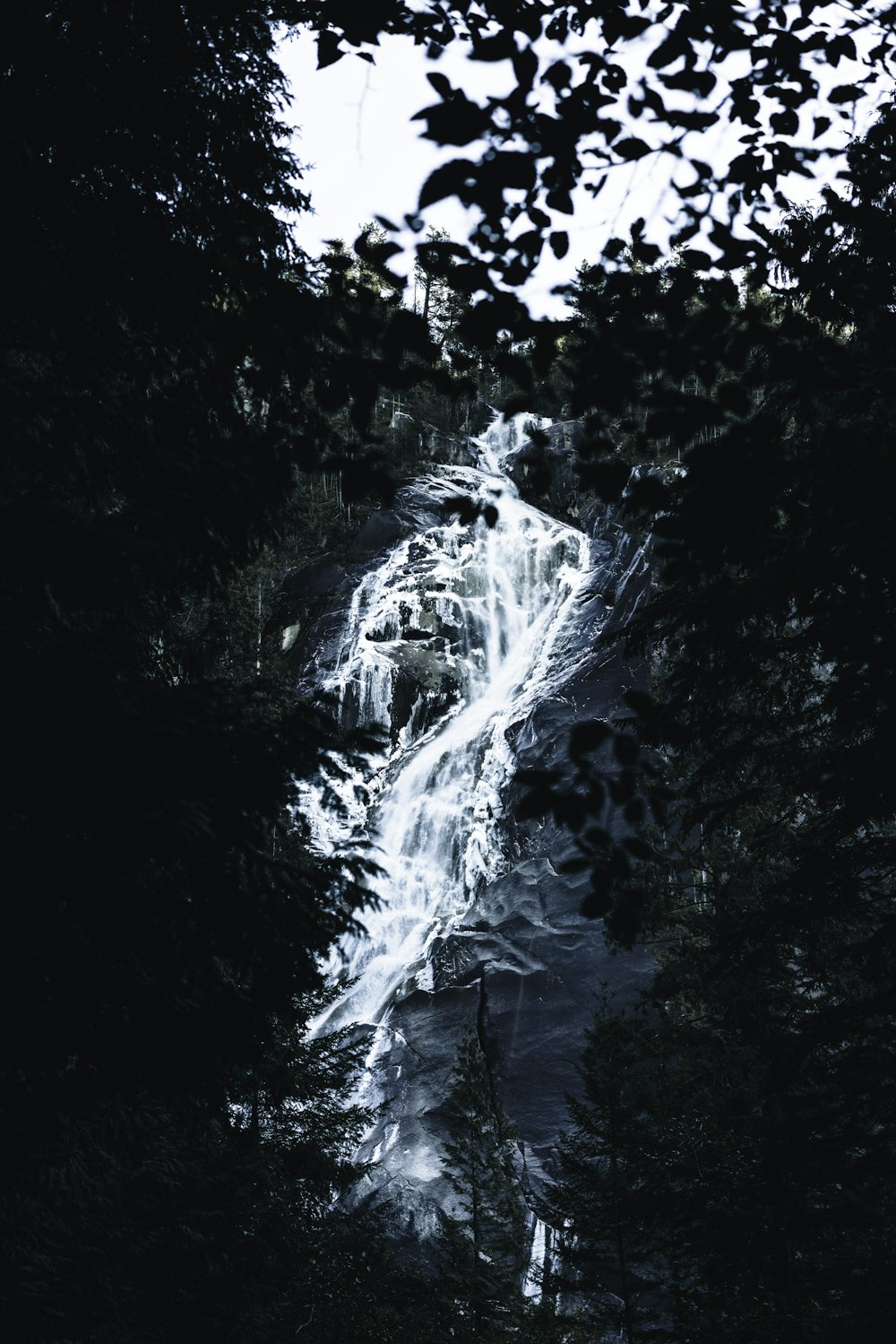 a very tall waterfall surrounded by trees