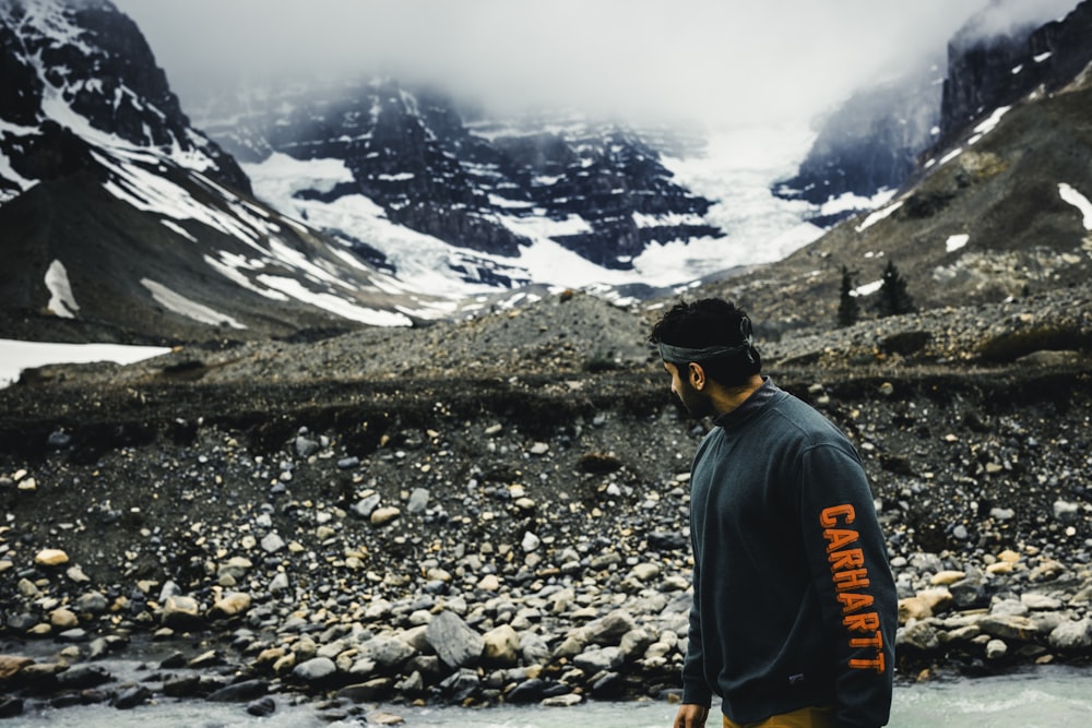 a man standing in a river with mountains in the background