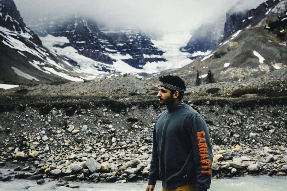 a man standing in a river with mountains in the background