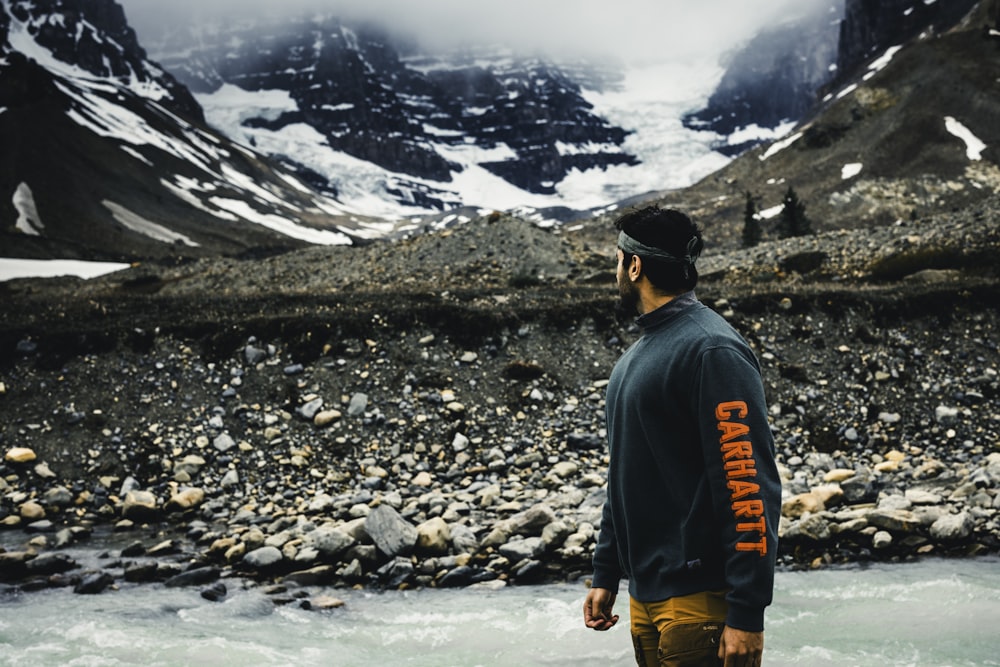 a man standing in a river with mountains in the background