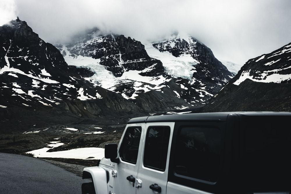 a white jeep parked on the side of a mountain road