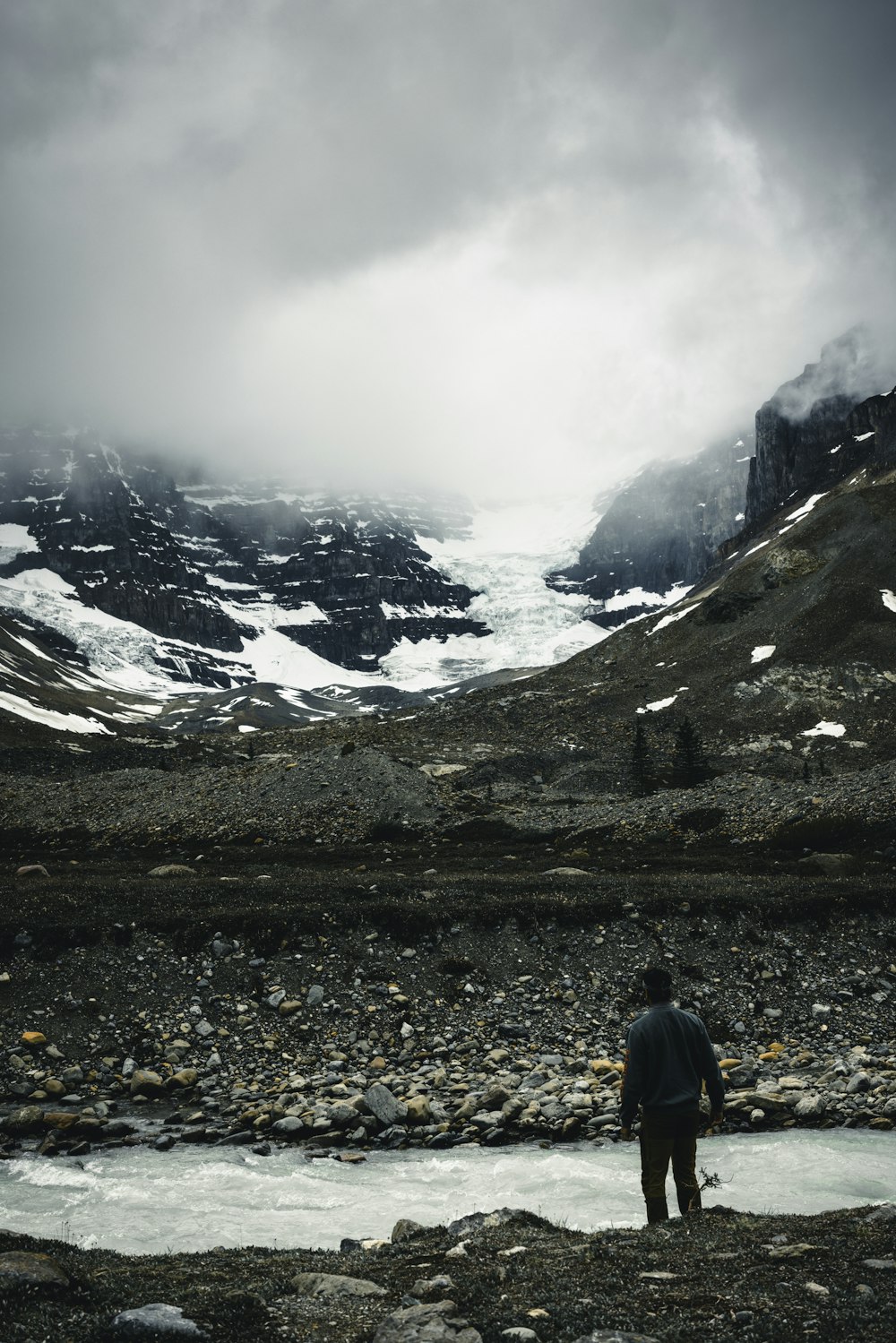 a man standing in a rocky field next to a mountain