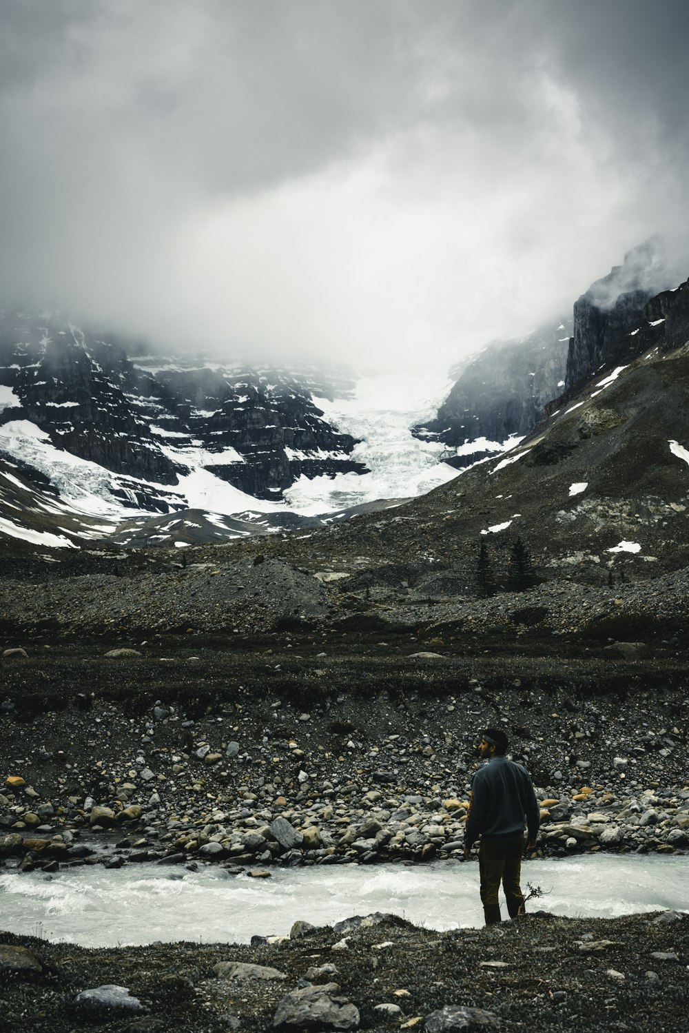 a man standing in the middle of a mountain stream