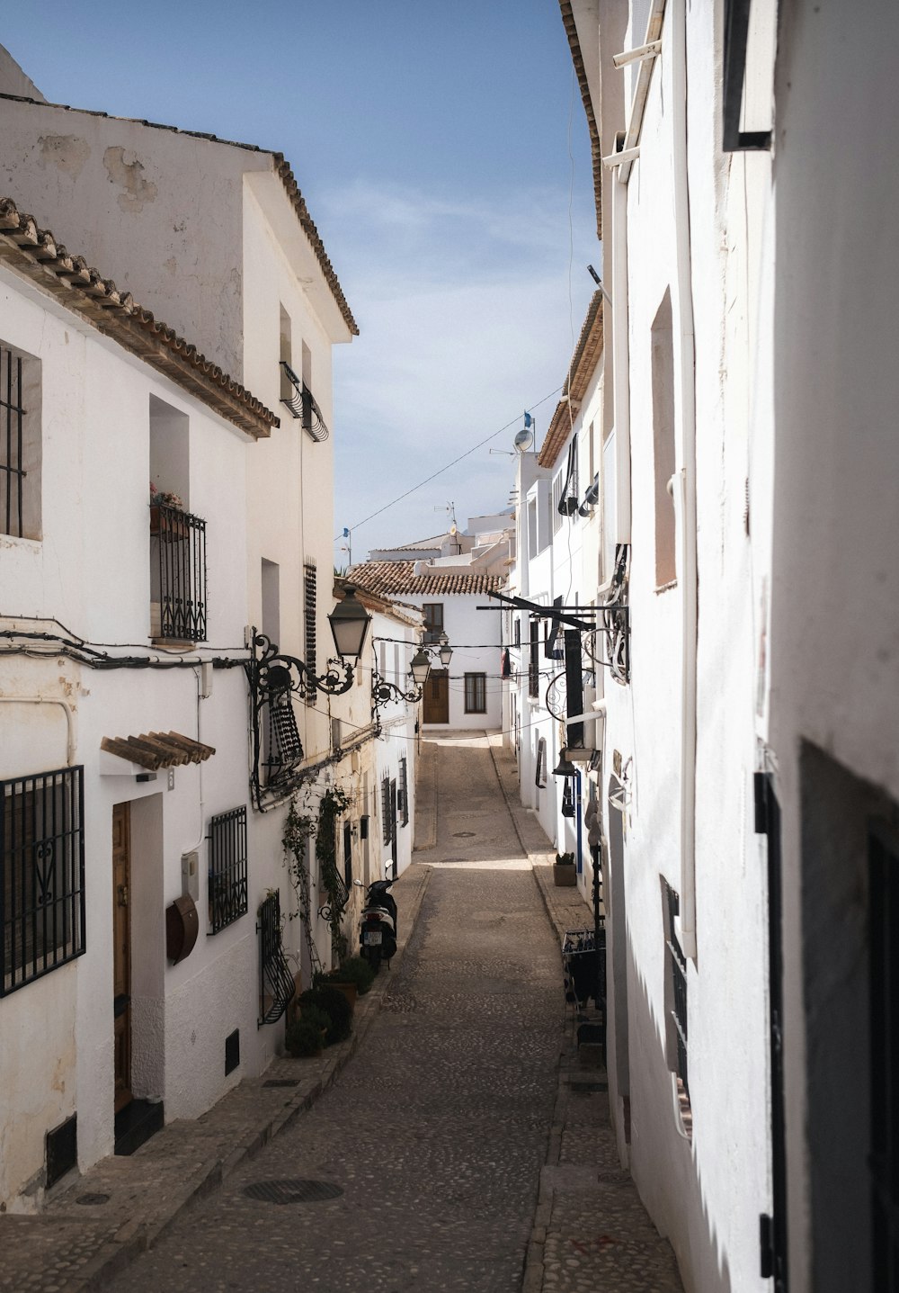 a narrow street with white buildings and a sky background