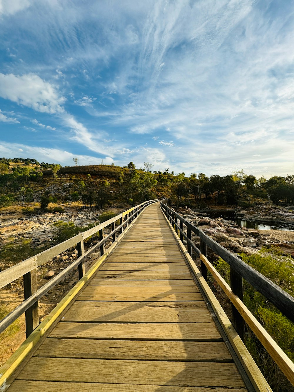 a wooden bridge over a river with a sky background