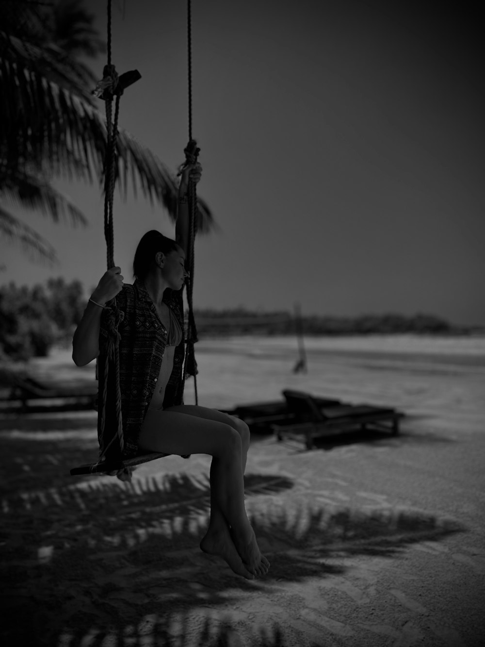 a woman sitting on a swing at the beach