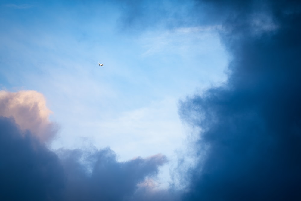 a plane flying through a cloudy blue sky