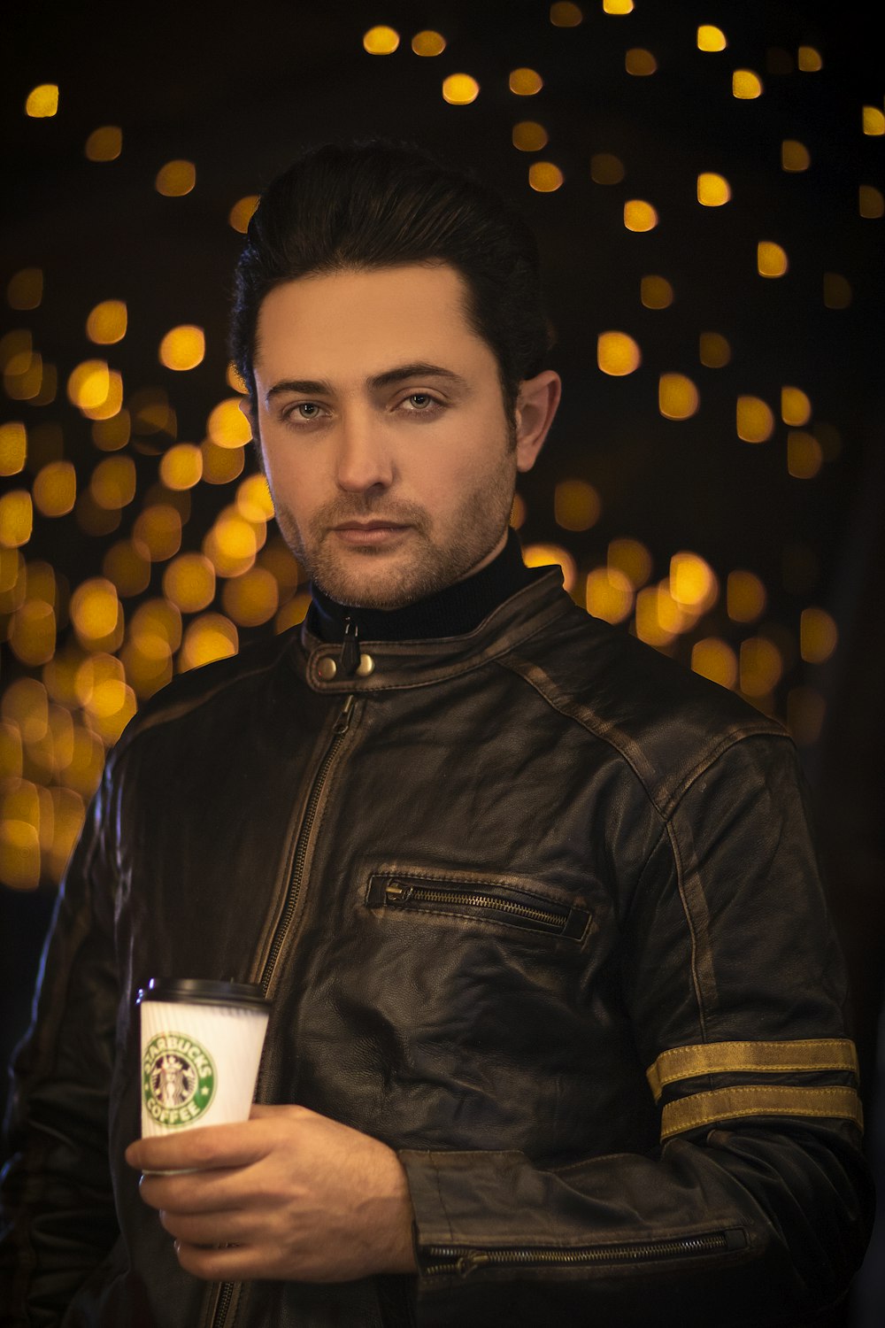 a man in a leather jacket holding a cup of coffee