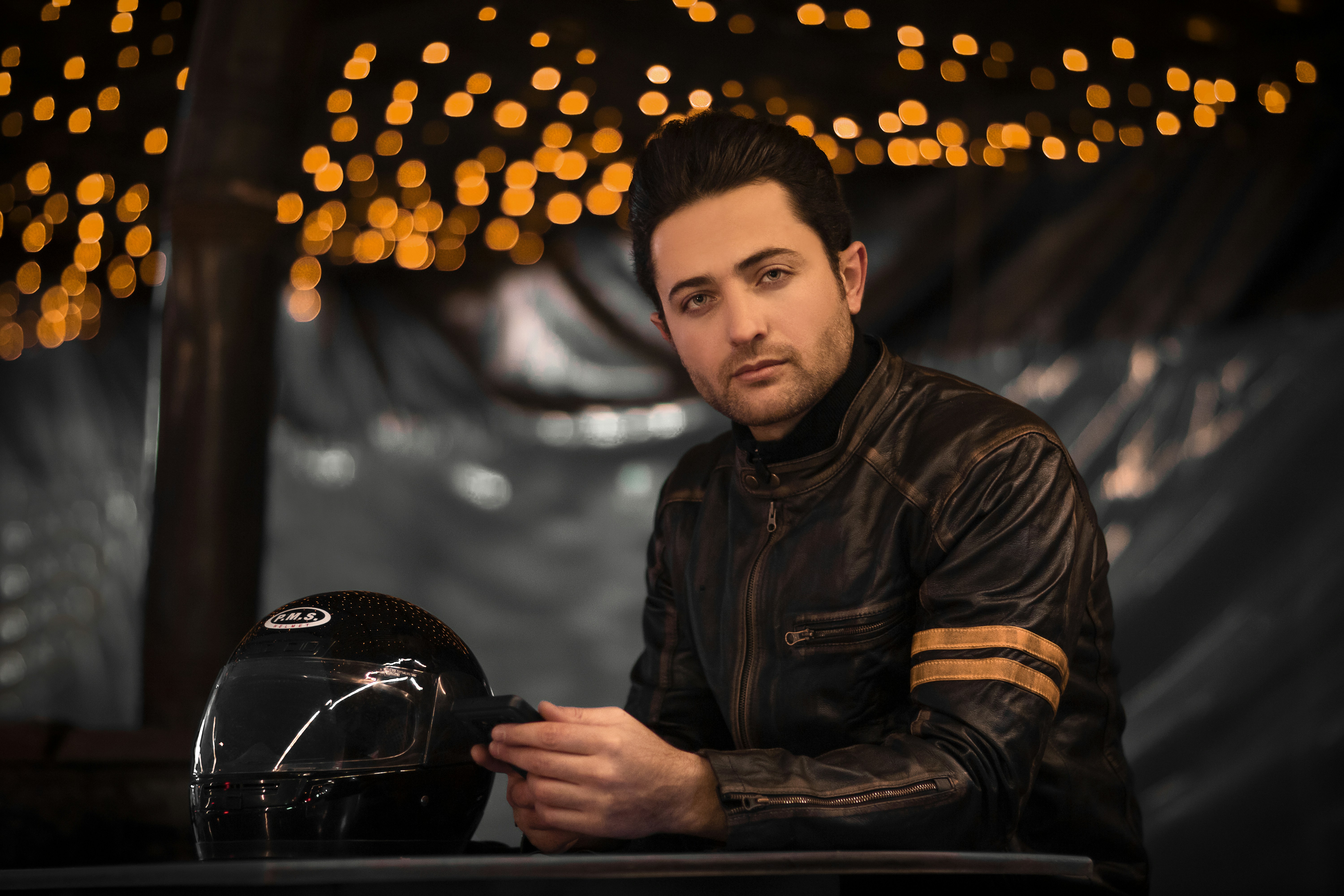a man sitting at a table next to a motorcycle helmet
