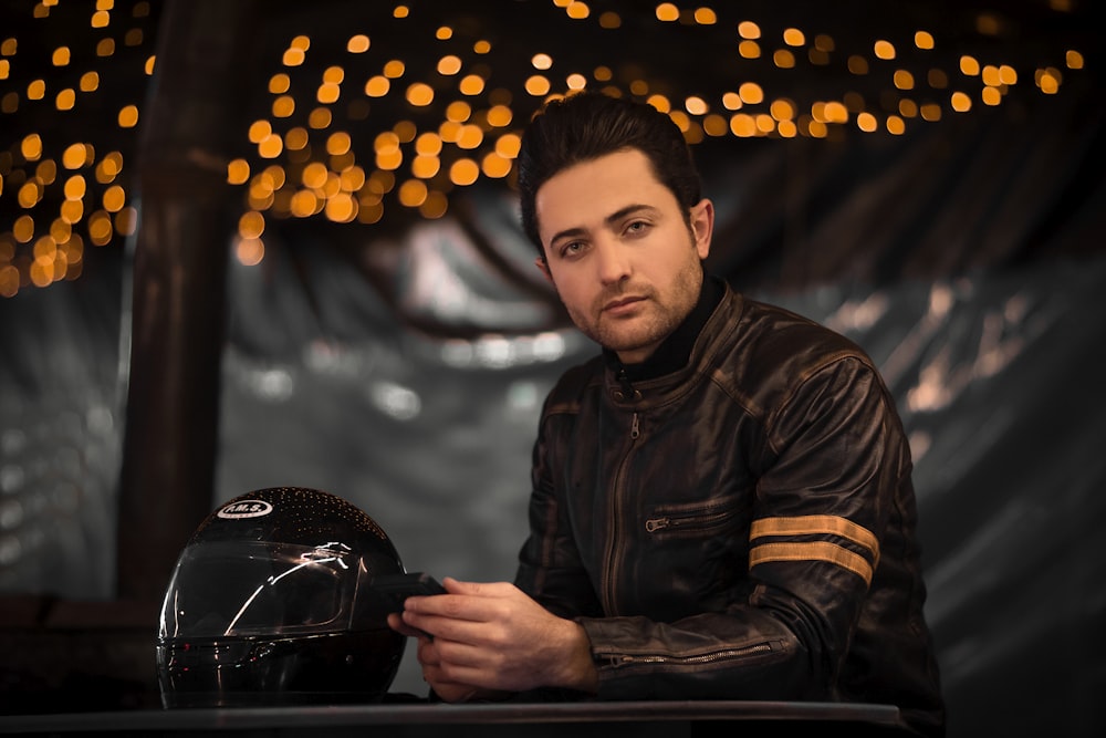 a man sitting at a table next to a motorcycle helmet