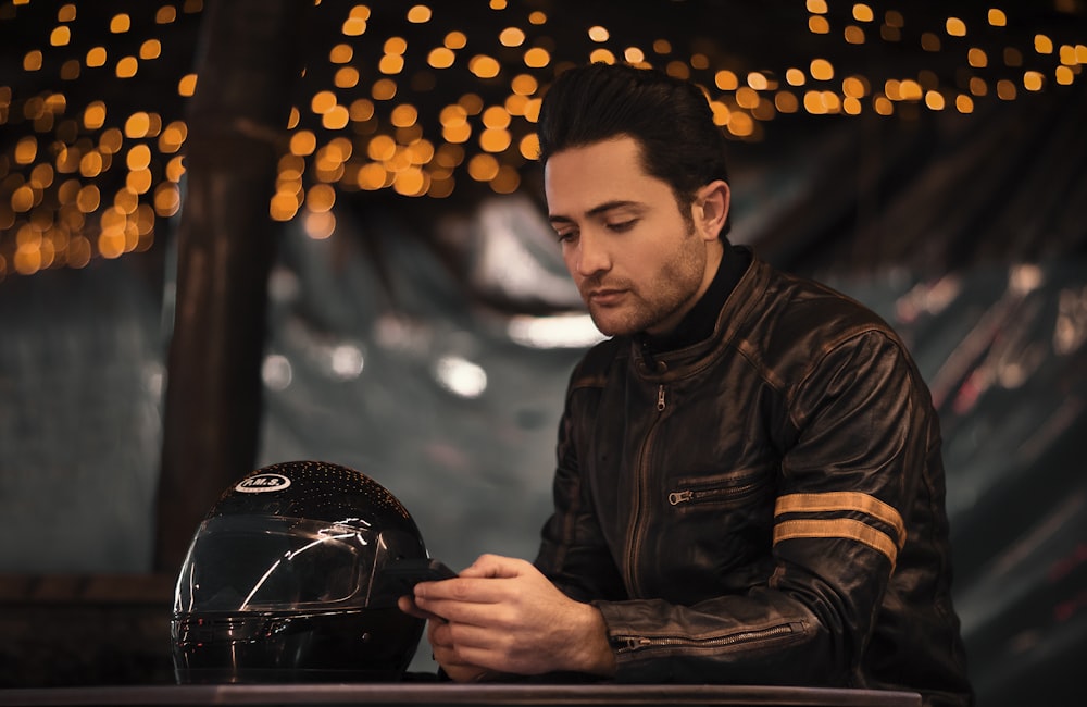 a man in a leather jacket looking at a helmet
