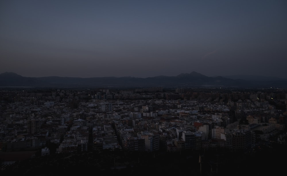 Una vista de una ciudad por la noche con montañas al fondo