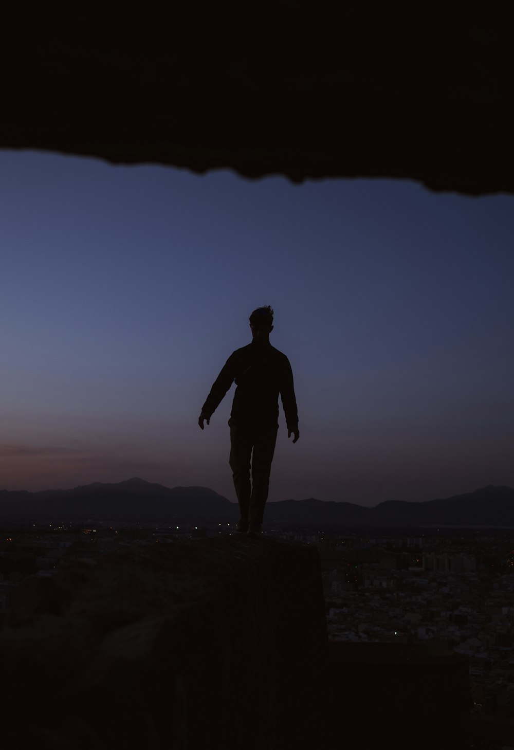 a man standing on top of a cliff at night