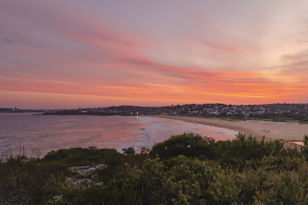 a sunset view of a beach with a city in the distance