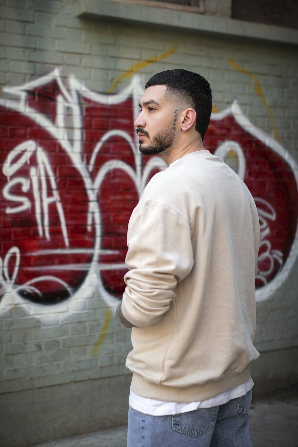 a man standing in front of a graffiti covered wall