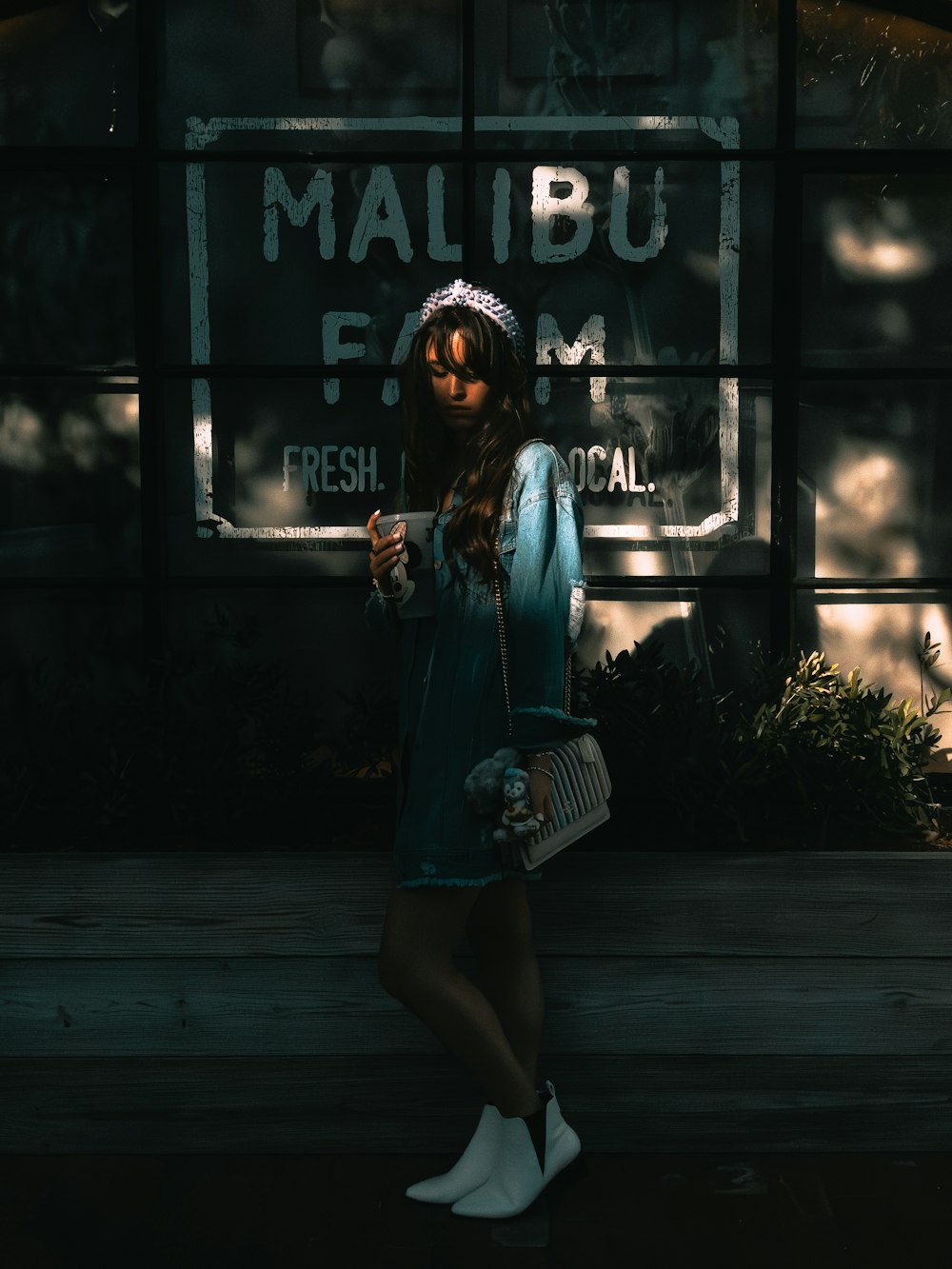 a woman standing in front of a sign holding a purse
