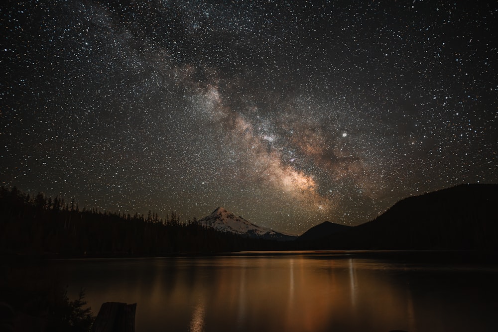 the night sky is filled with stars above a lake