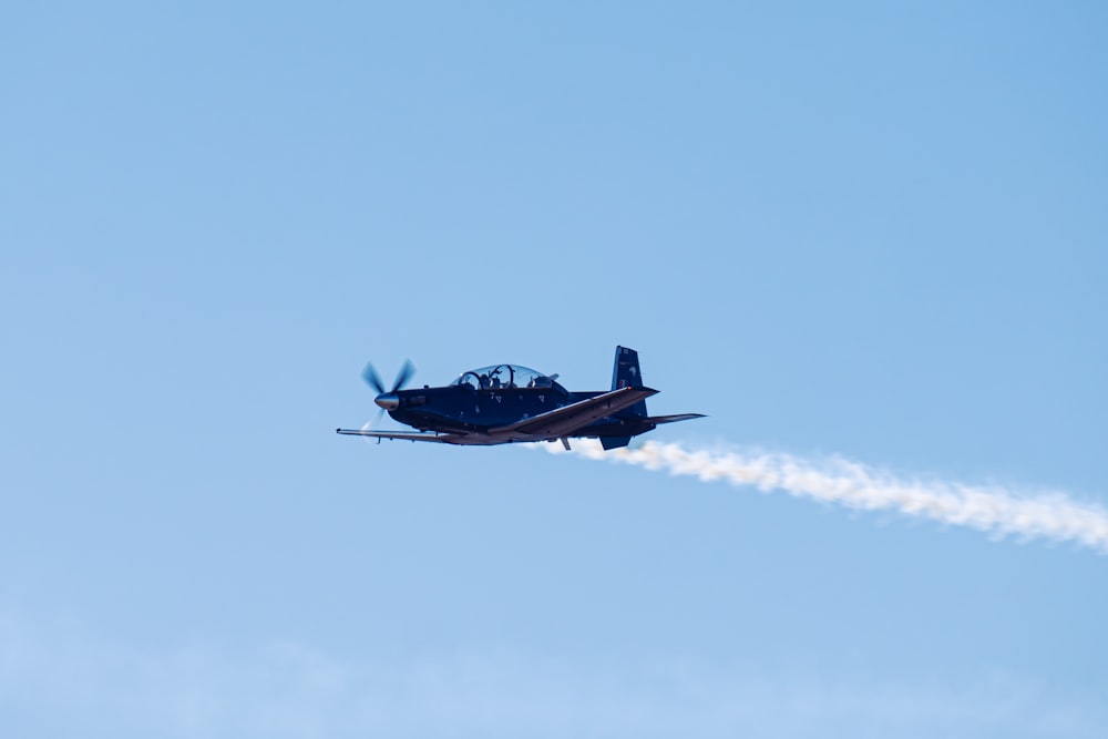 a small airplane flying through a blue sky